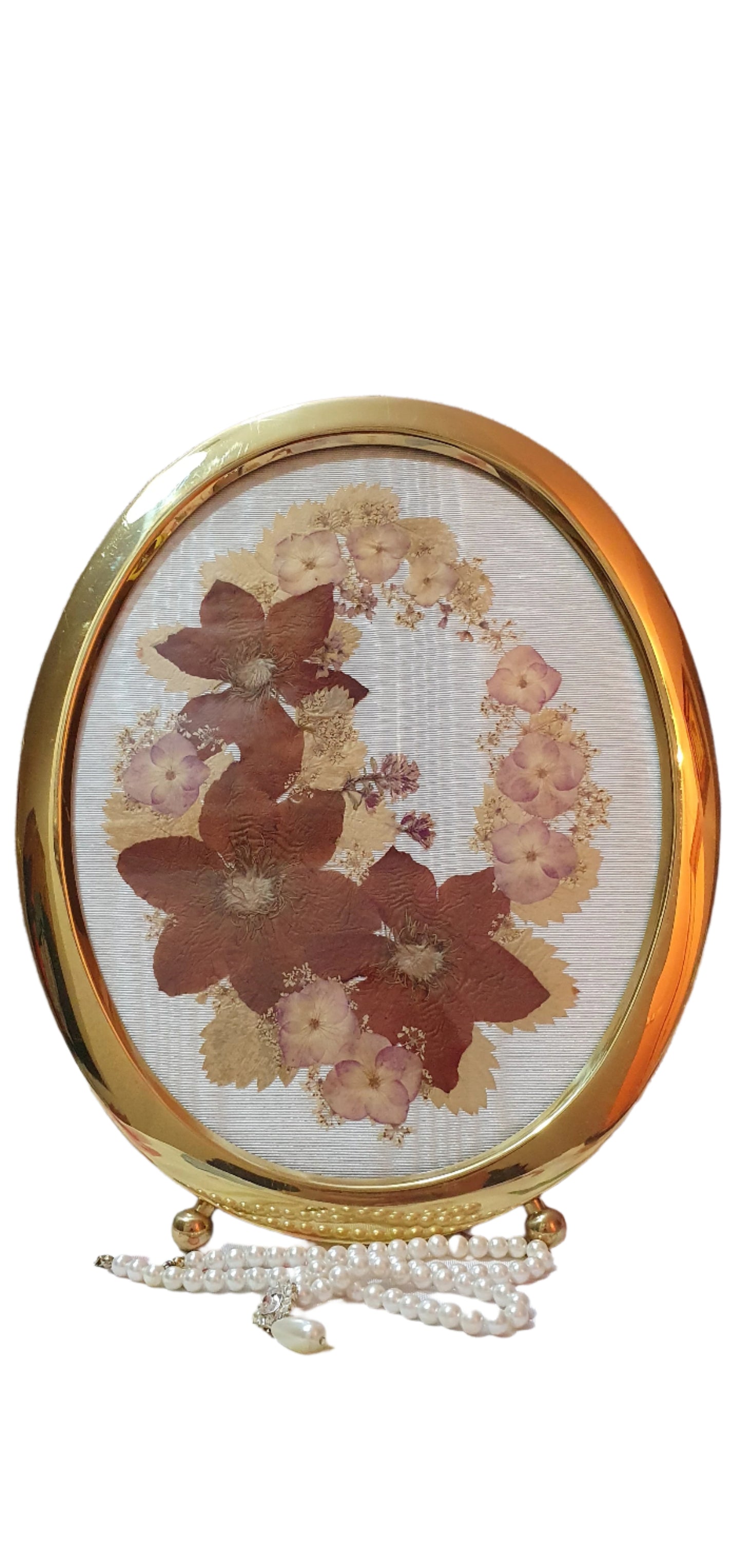 Brass oval frame with arrangement of dried pressed flowers