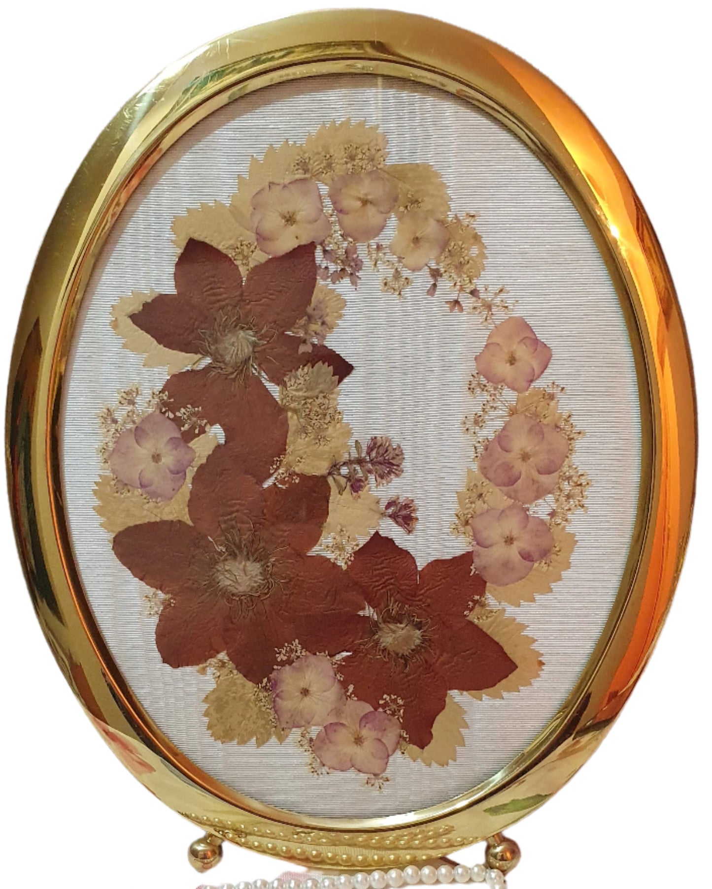 Brass oval frame with arrangement of dried pressed flowers