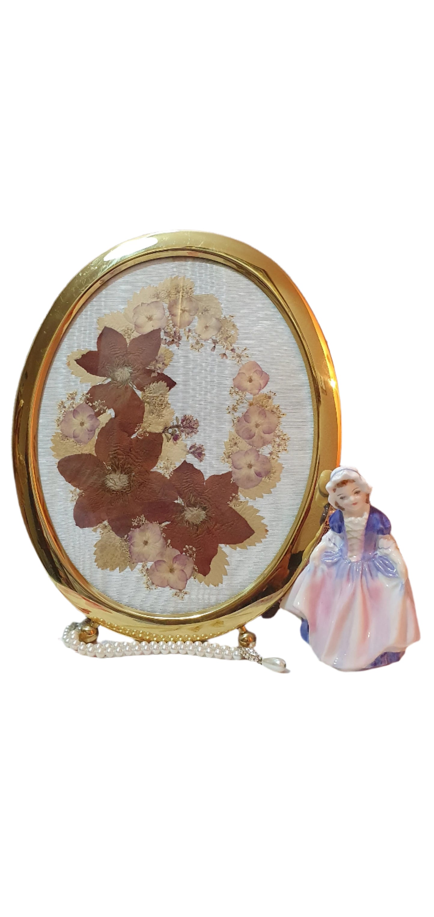 Brass oval frame with arrangement of dried pressed flowers