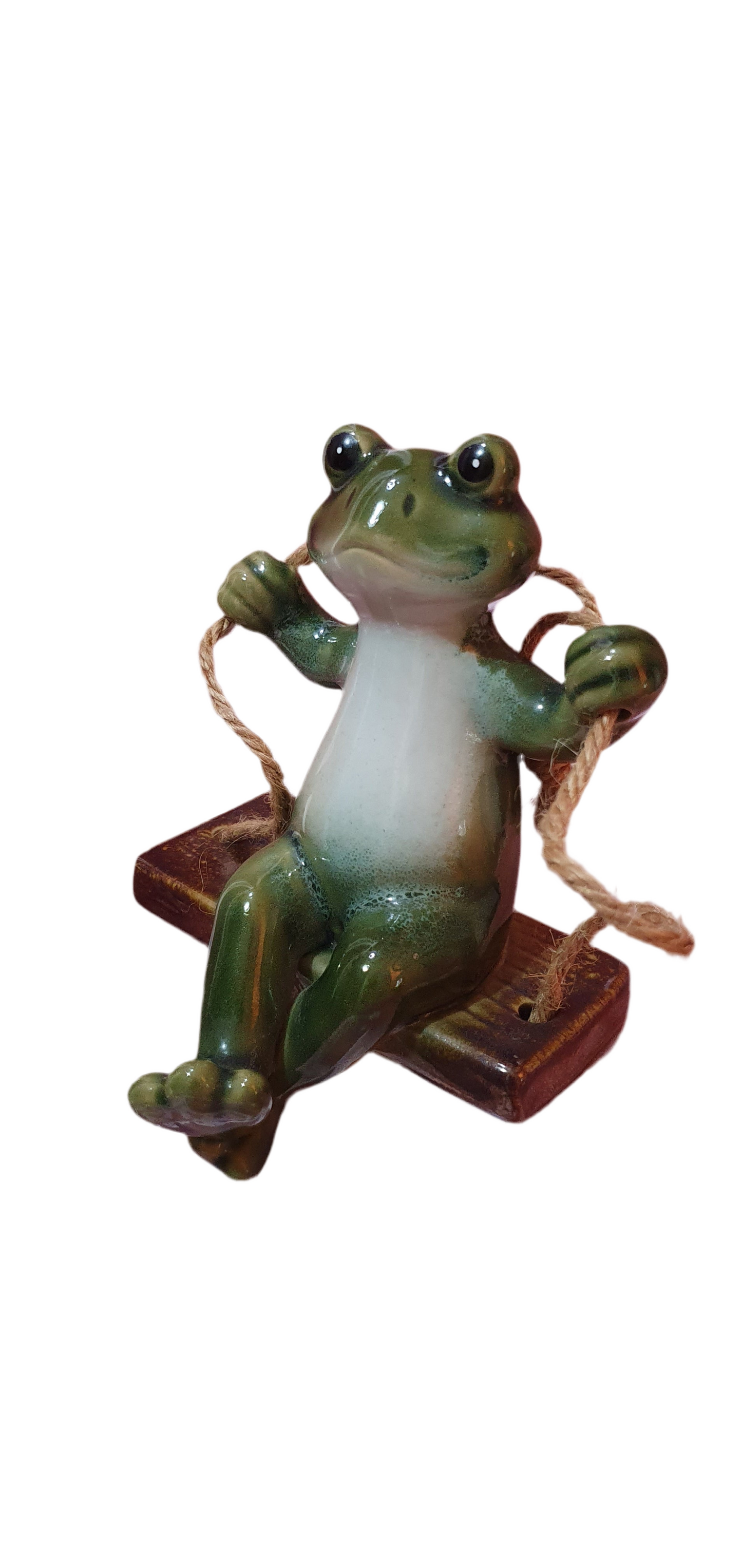 Cheerful ceramic frog on a swing
