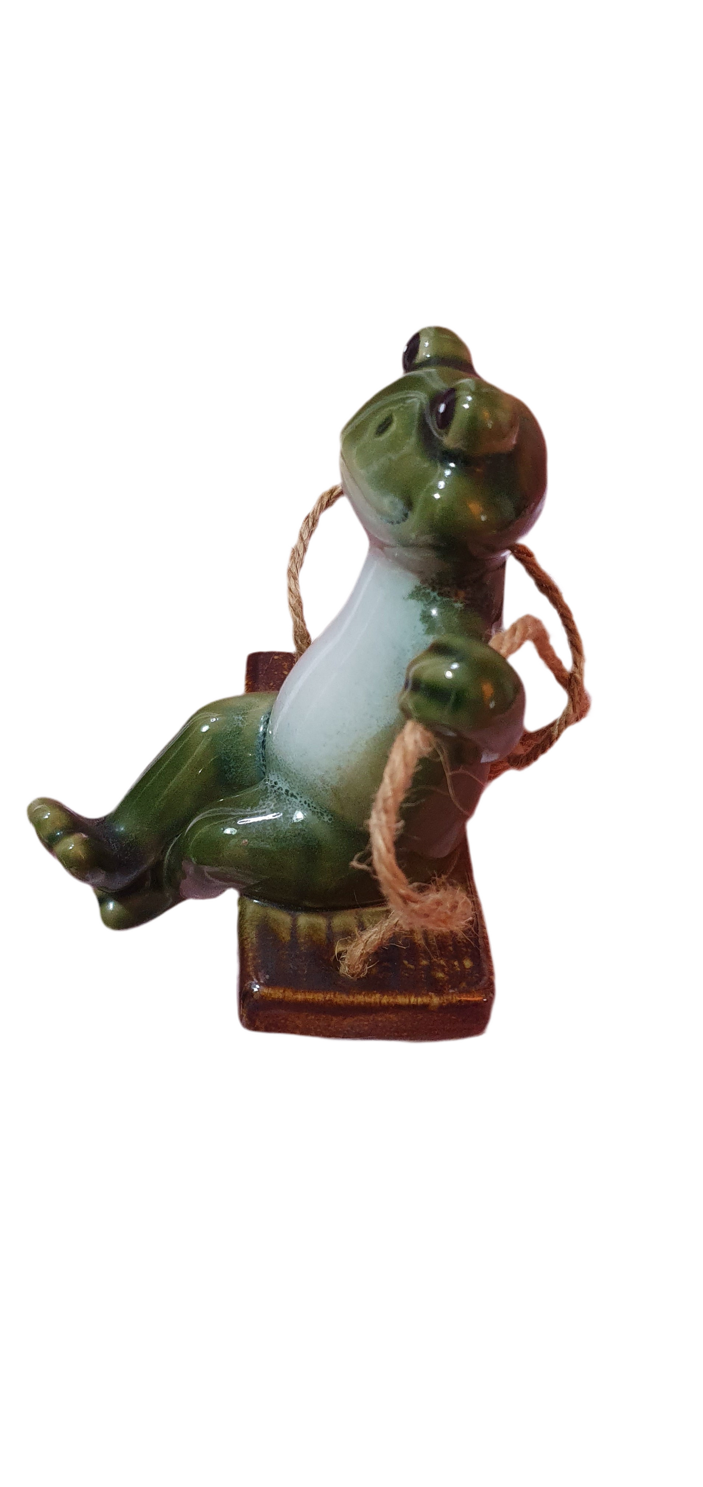 Cheerful ceramic frog on a swing